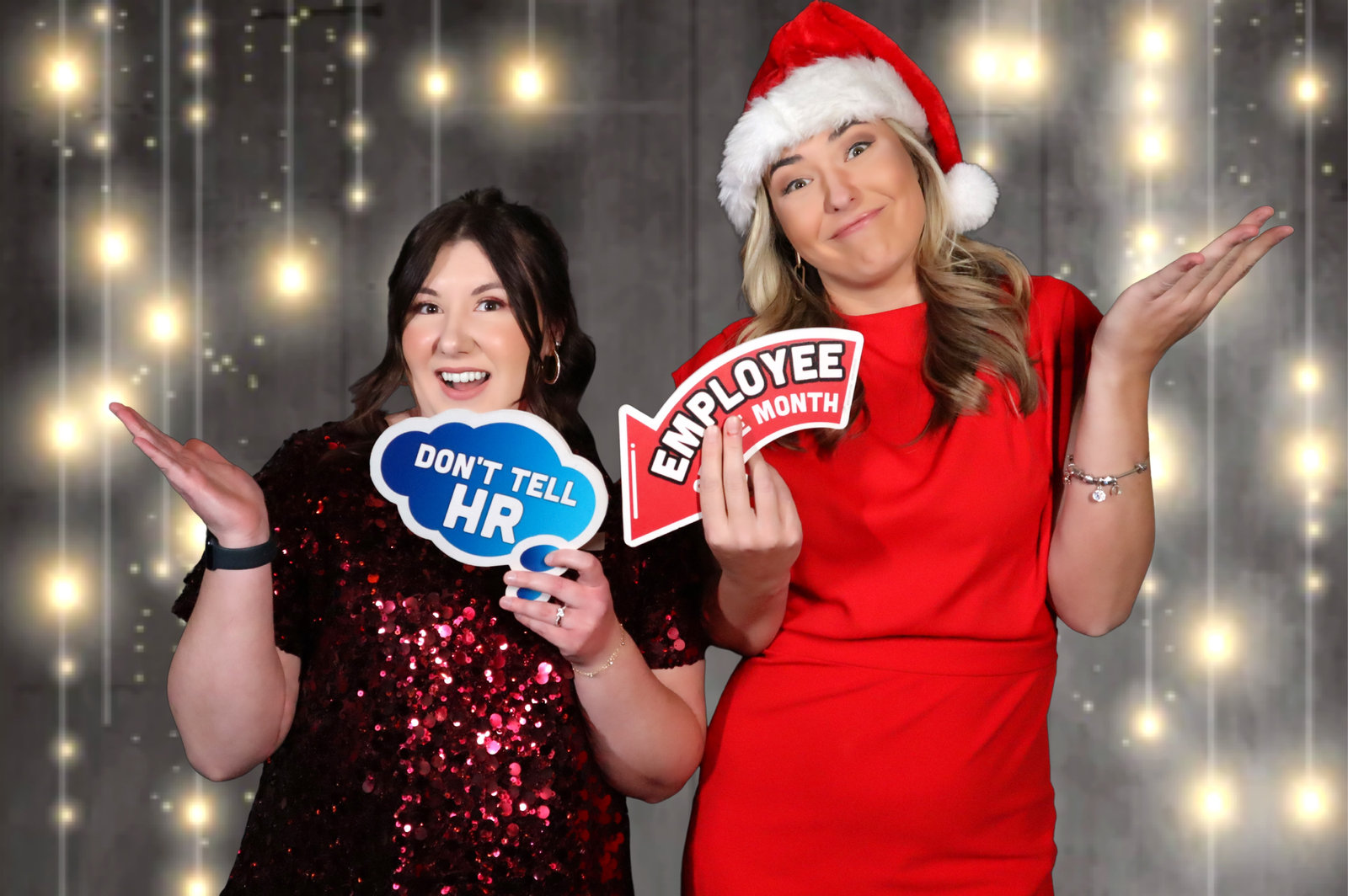 Coworkers in Santa hats laughing with Don’t Tell HR signs at a company holiday party