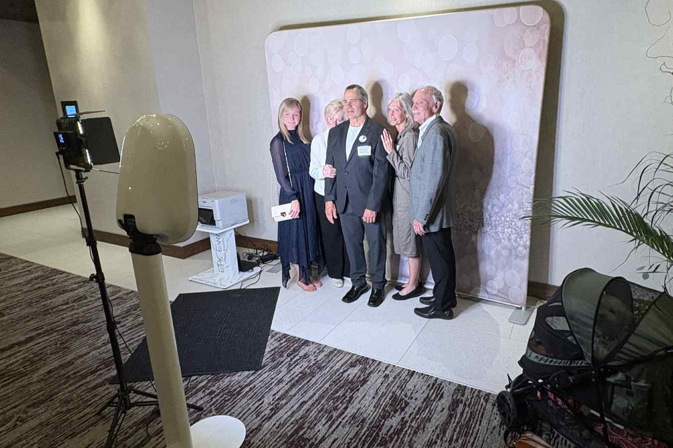 A booth set up in front of a soft white backdrop with guests posing at a corporate event
