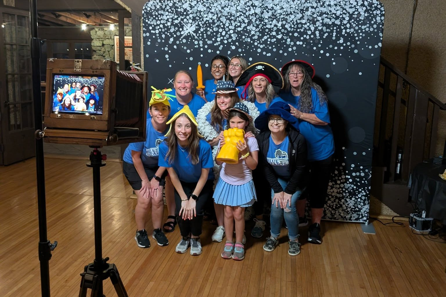 A group in party props posing in front of the Heirloom camera booth