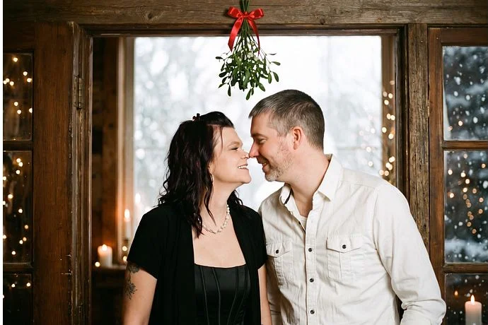 A couple under the mistletoe by a snowy window