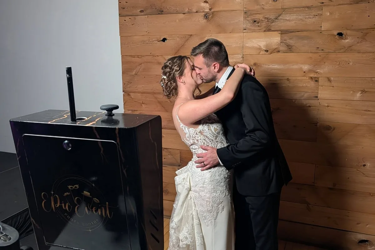 Bride and groom kissing beside the black and gold Onyx booth