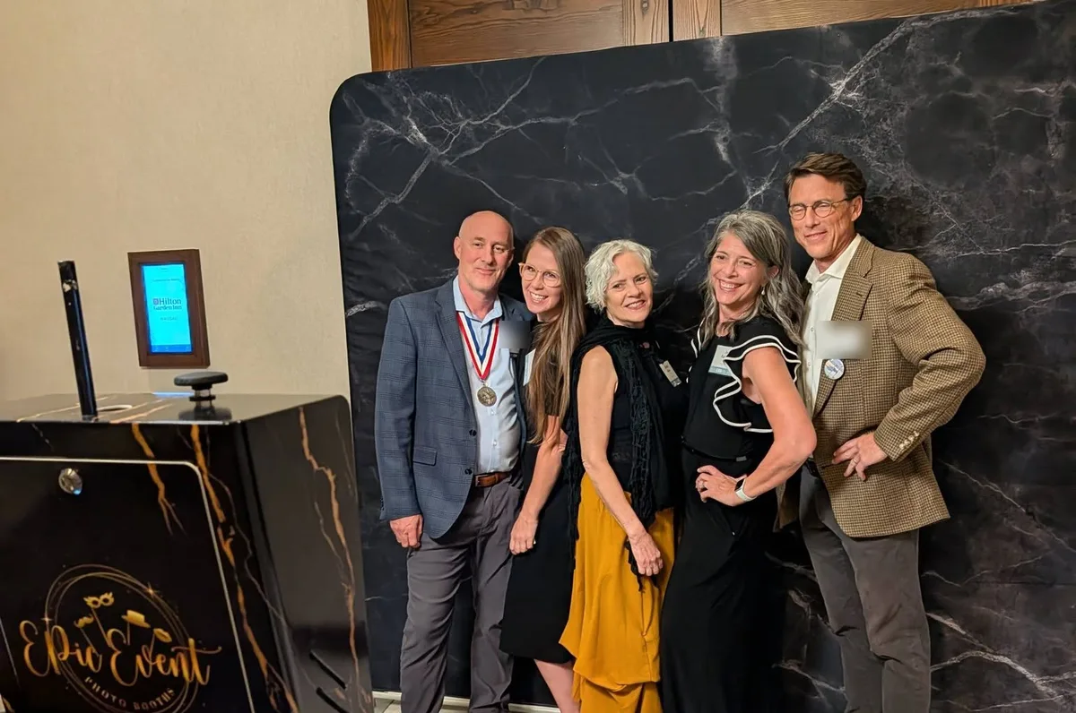 Five guests posing at the Onyx booth in front of a black marble backdrop at a hotel event
